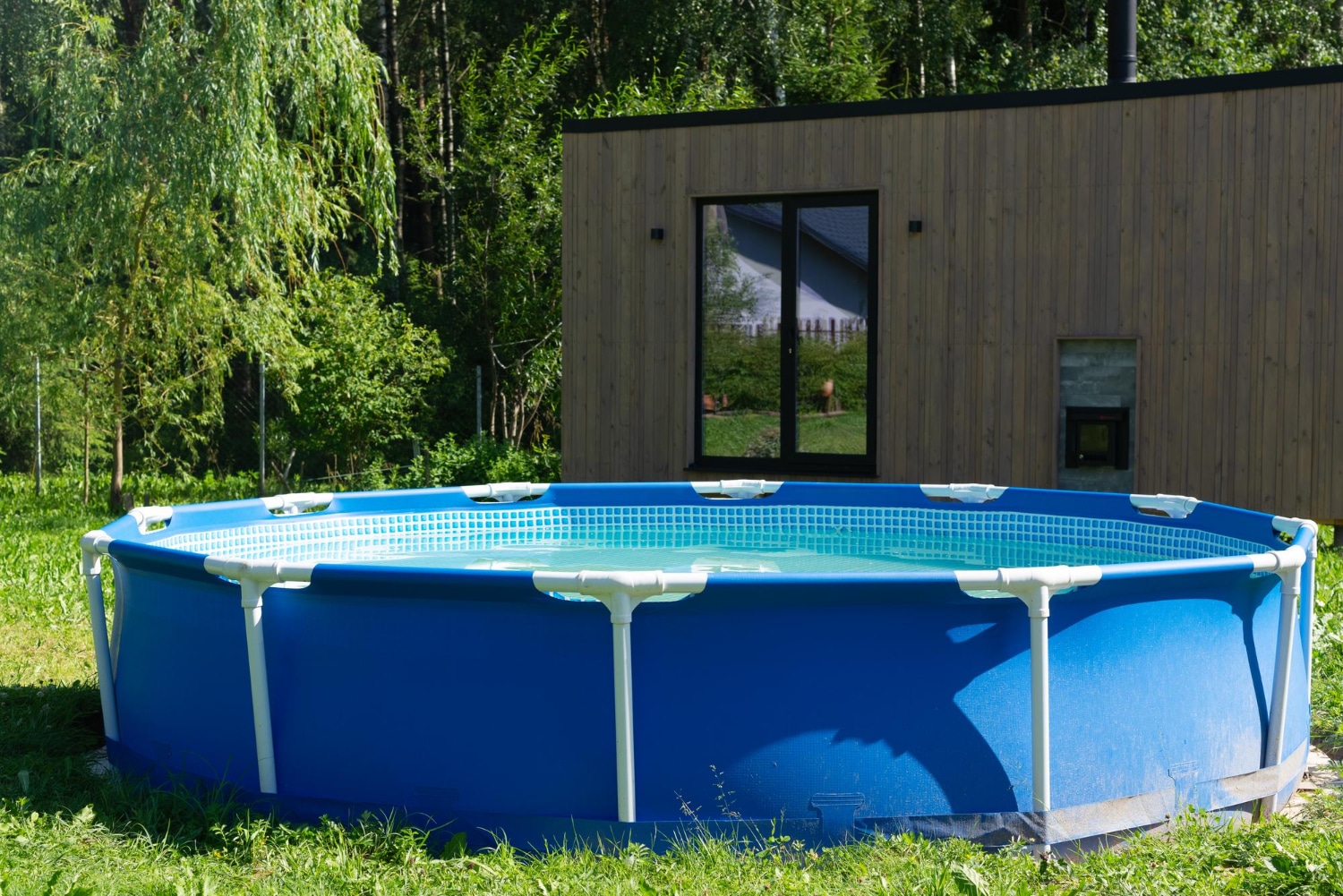 Une piscine hors sol est installée dans le jardin d'une habitation.